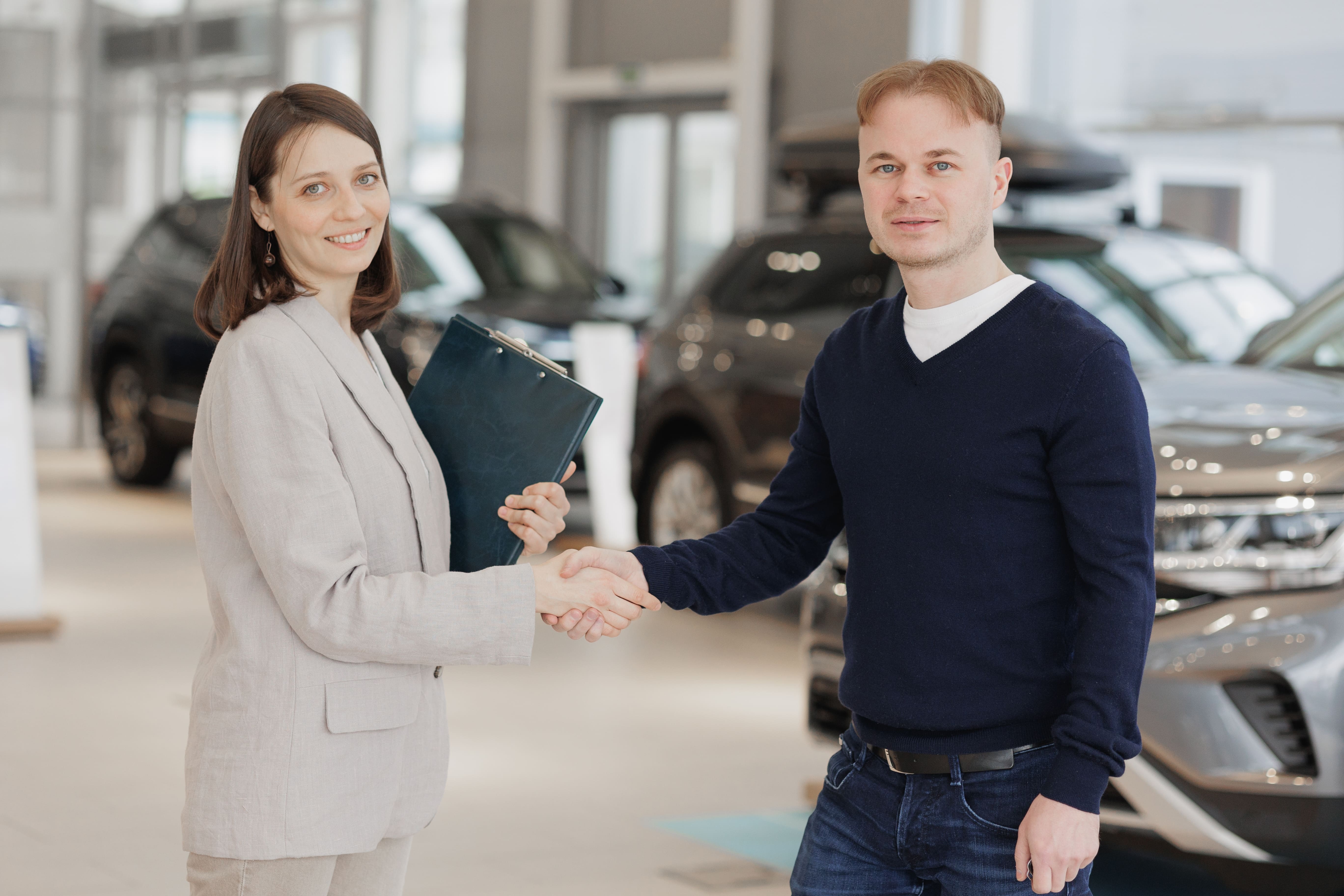 Pareja revisando un coche de segunda mano con un mecánico, analizando detalles y asesorándose para una compra segura
